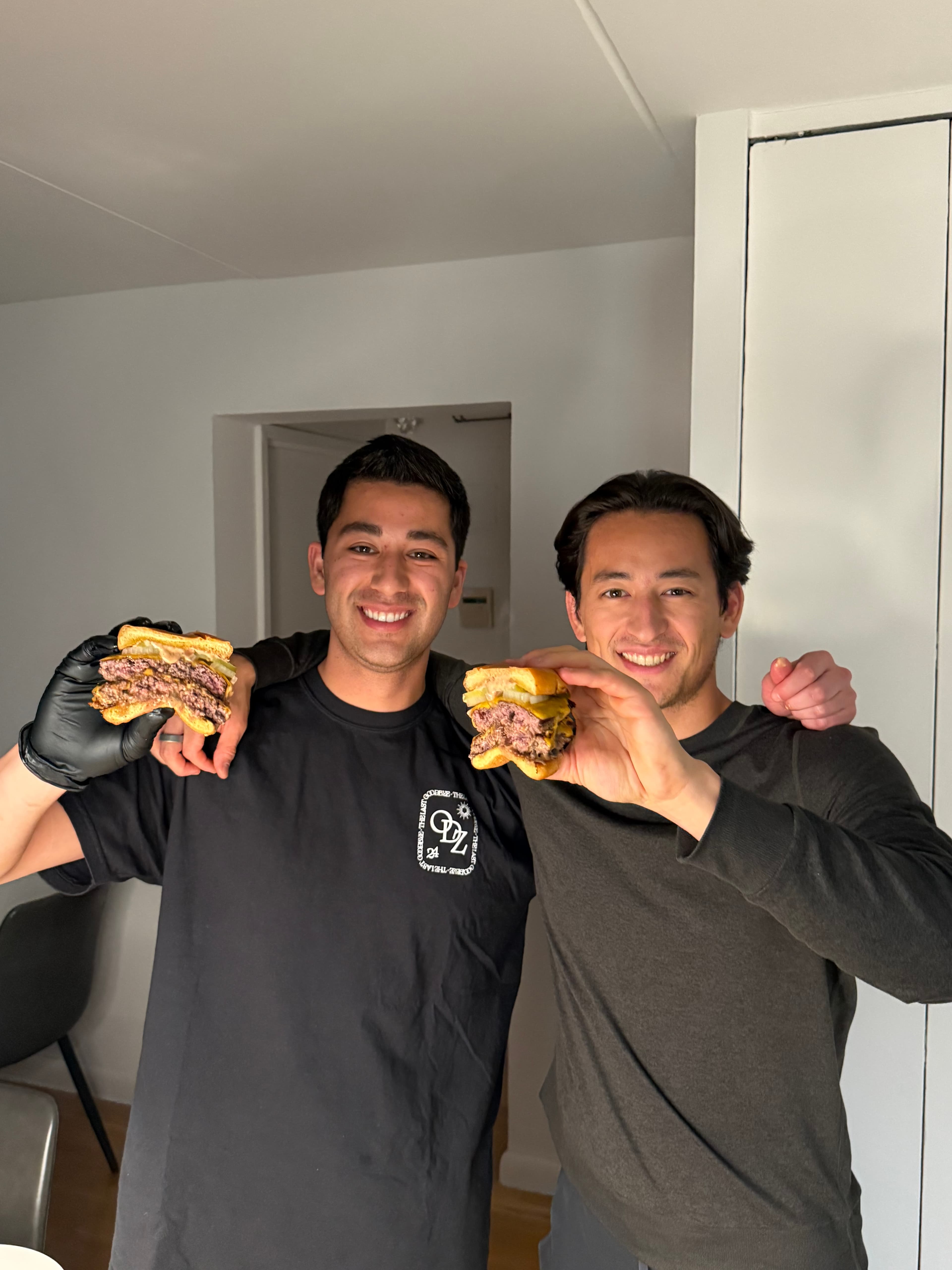 The two brothers behind Brotherly Burgers, each holding a smash burger